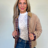 Front view of tan quilted barn jacket with red plaid lining and corduroy collar from shear boutique fall collection. Model is showing inside pattern detail