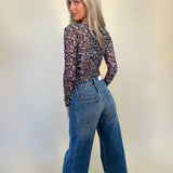 back full length view of caleb high rise relaxed stacked waist jeans and back of mesh print top- shear boutique fall collection