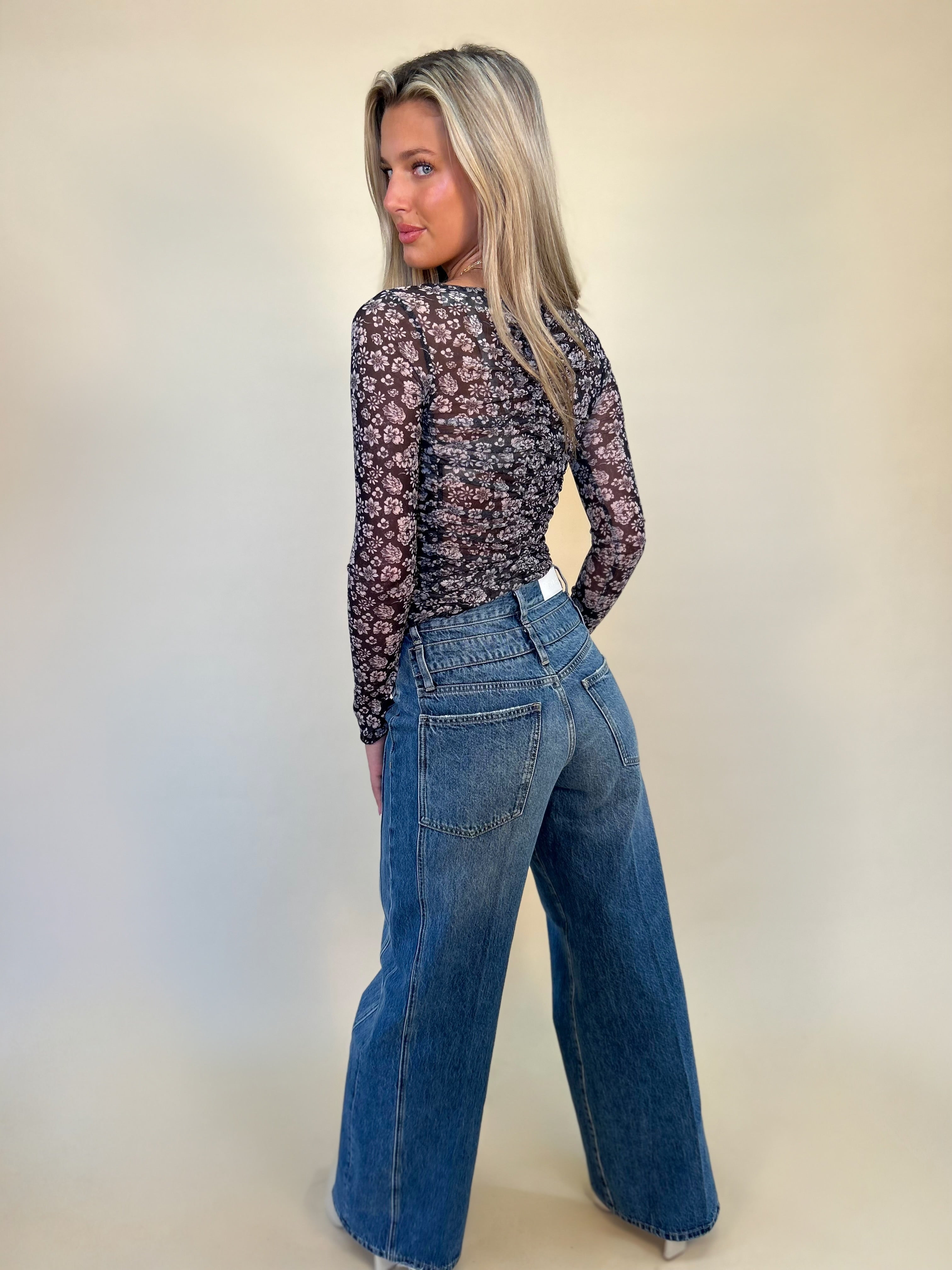 back full length view of caleb high rise relaxed stacked waist jeans and back of mesh print top- shear boutique fall collection