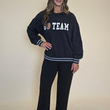 Cozy black Z Supply "Go Team" pullover featuring bold white sleeve stripes and an oversized silhouette inspired by vintage football jerseys.