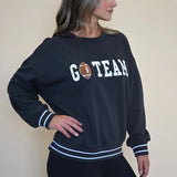 Black oversized Z Supply crew neck with athletic white stripes on the sleeves, blending comfort with a sporty football-inspired design.