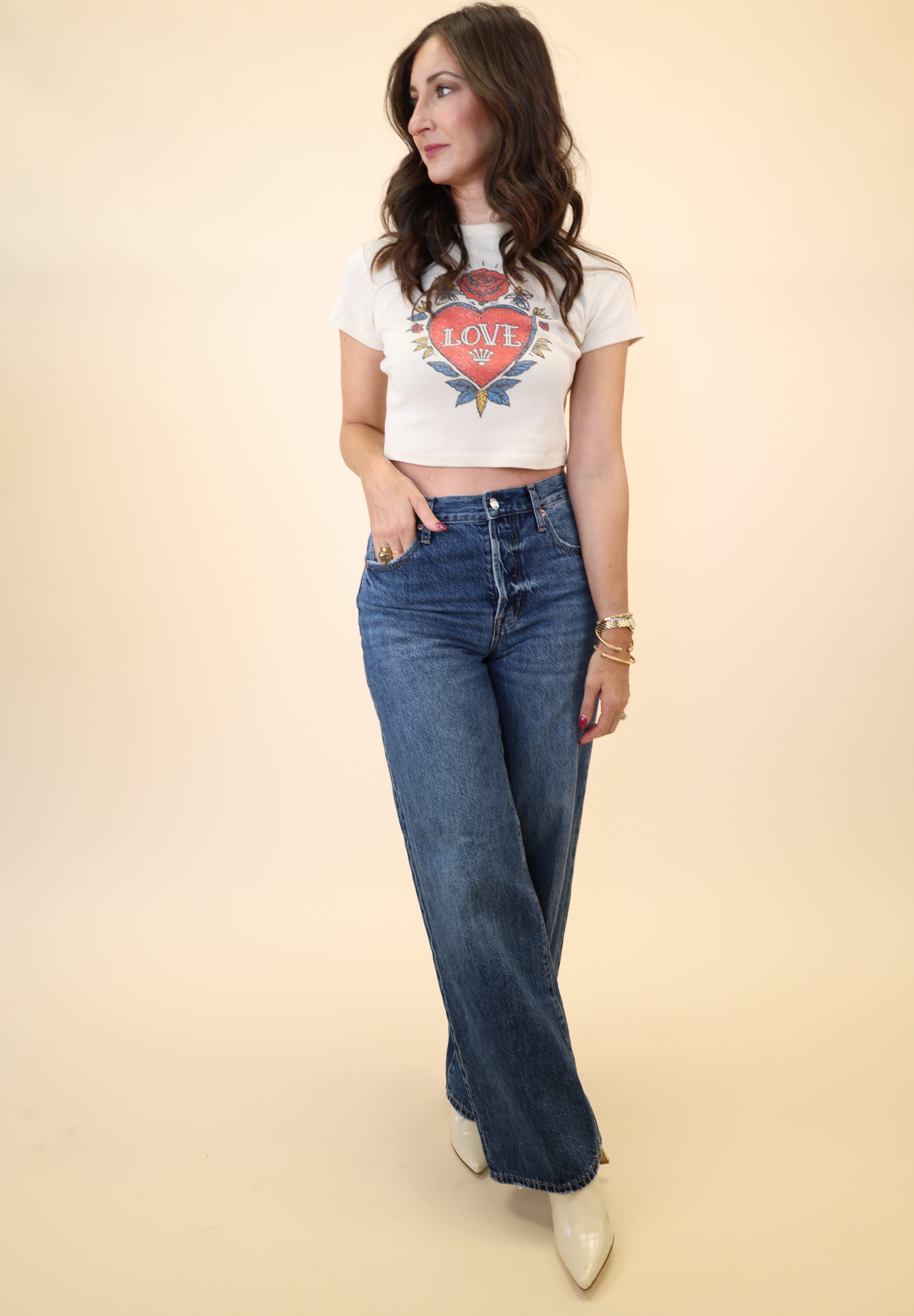 Soft white baby tee with vintage heart tattoo graphic reading “Love” by Girl Dangerous