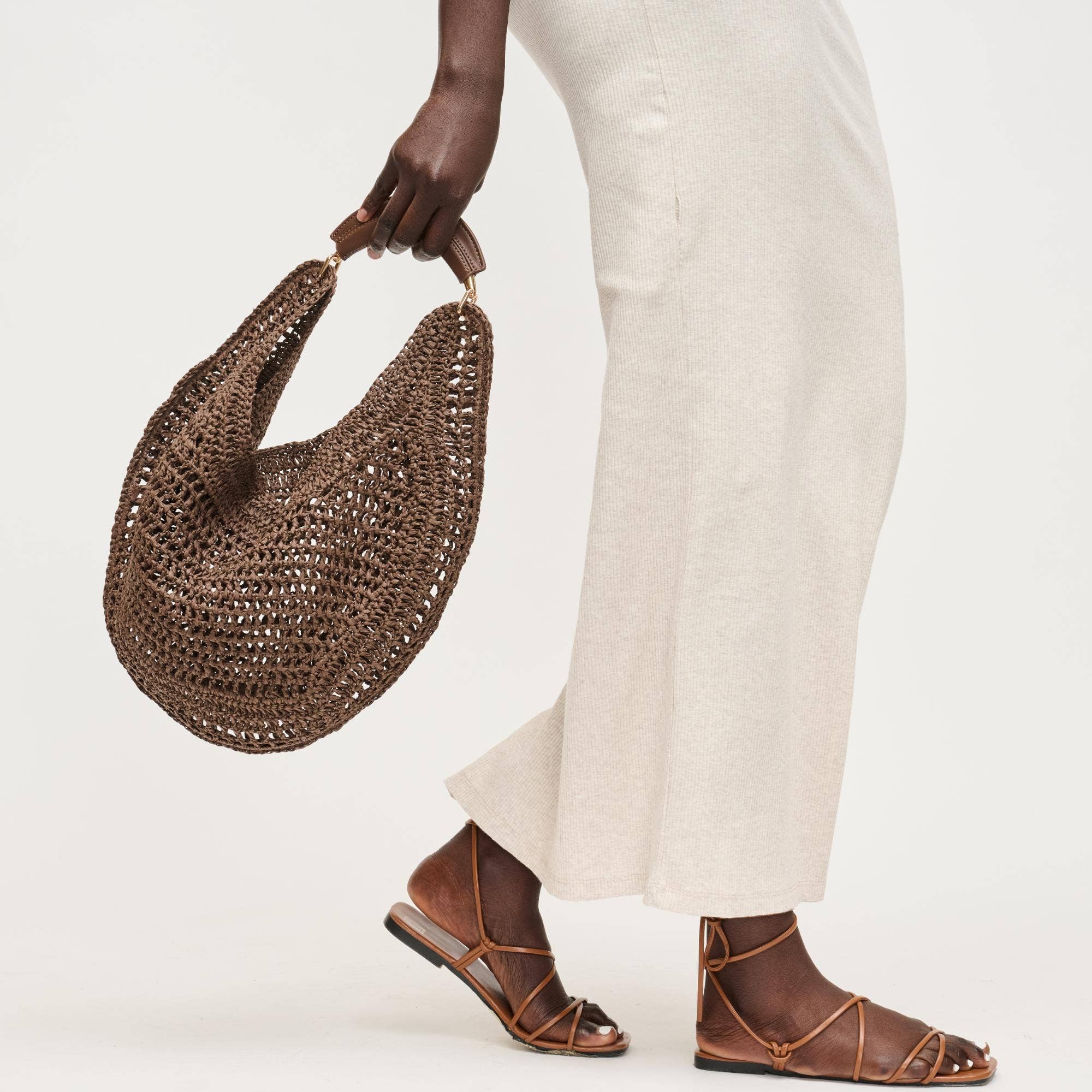 Slouchy chocolate brown straw shoulder bag with padded handle and snap tab closure for an effortless coastal look