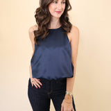 Model wearing Deluc Leonard Top in navy satin with bloused cropped hem and sleeveless tank silhouette.
