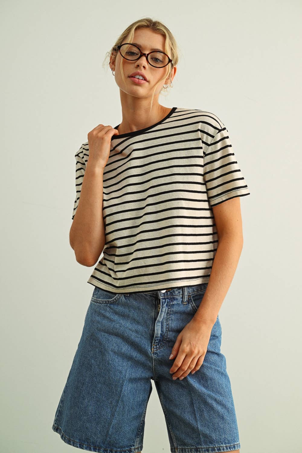Woman wearing a striped shirt and jeans against a plain background