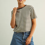 Woman wearing a striped shirt and jeans against a plain background