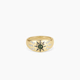 Gold statement ring featuring sunburst design with green gemstone center.