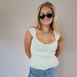 Pastel mint ribbed sweater top with wide straps, front buttons, and a slightly cropped, fitted style.
