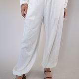 Breezy white wide-leg linen pants with side pockets and an adjustable elastic waistband with drawstring.