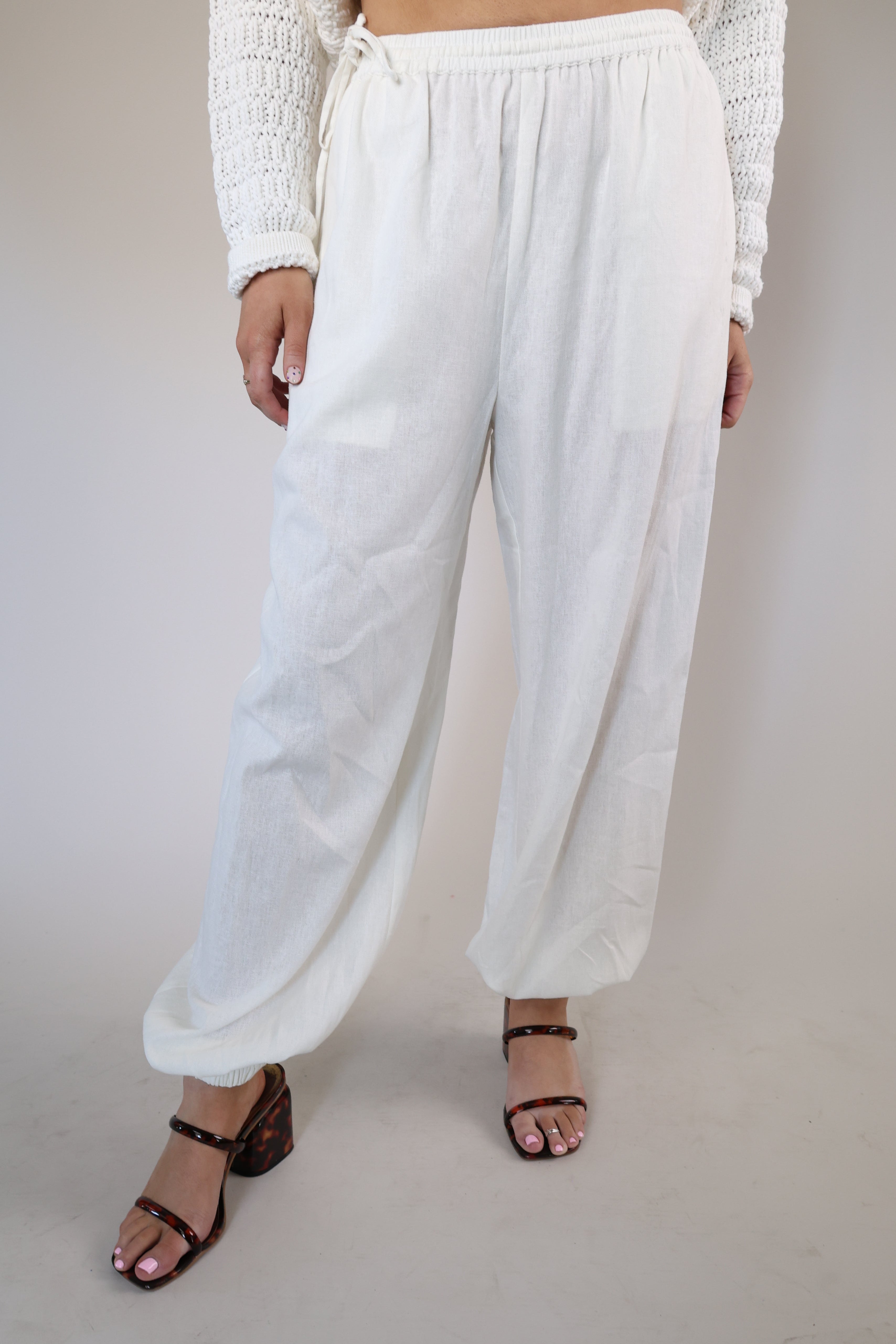 Breezy white wide-leg linen pants with side pockets and an adjustable elastic waistband with drawstring.