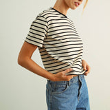 Woman wearing a striped shirt and denim shorts against a plain background