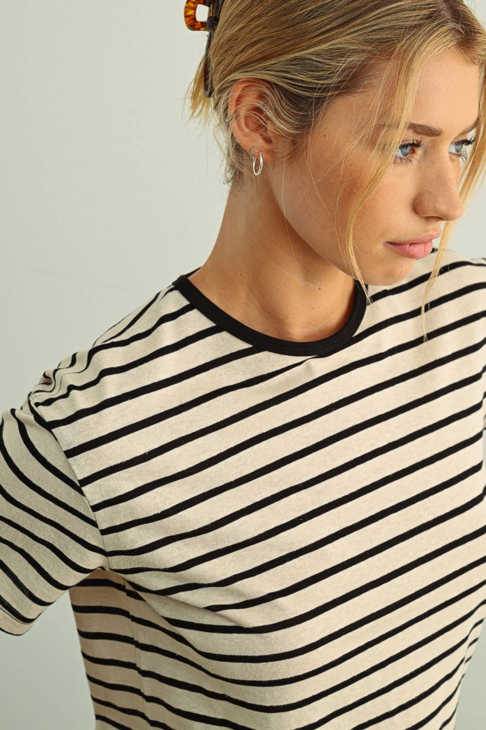 Woman wearing a black and white striped shirt against a plain background