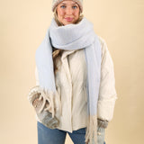 Super soft knit Free People Winter Chill blanket scarf in blue, designed for cozy layering with cream fringe edges.