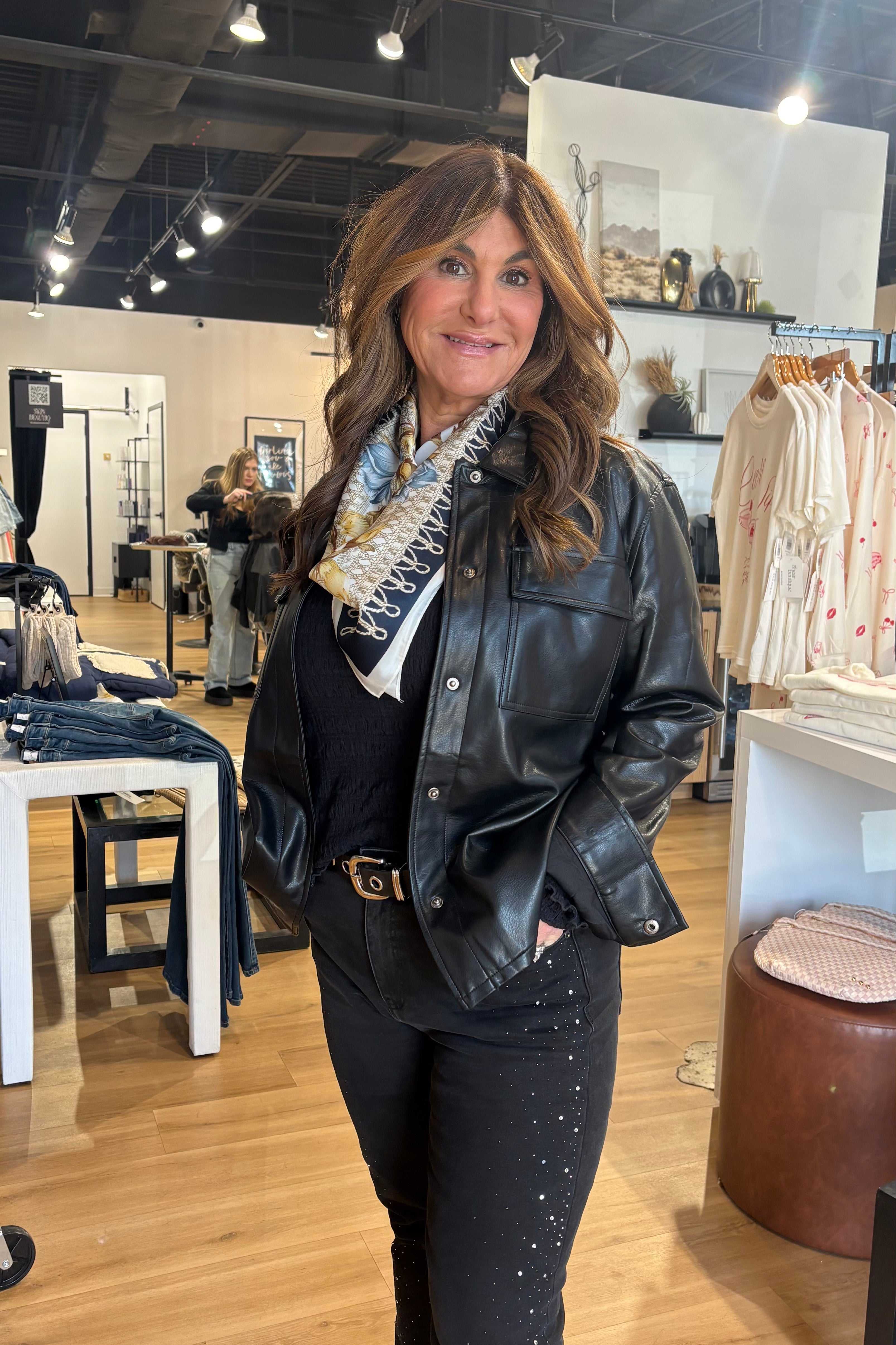 Woman in a store wearing a black leather jacket and scarf