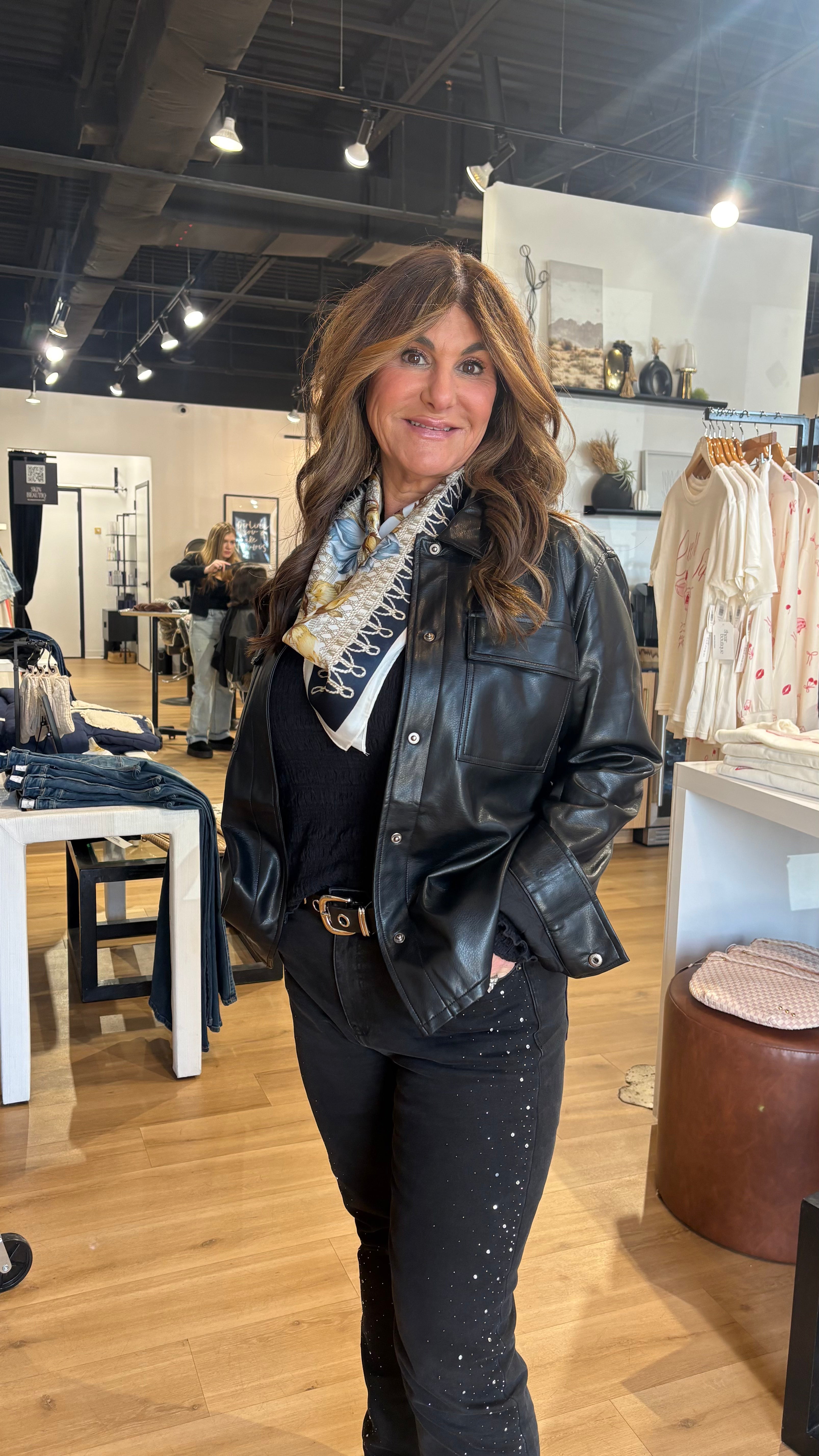 Woman in a store wearing a black leather jacket and scarf