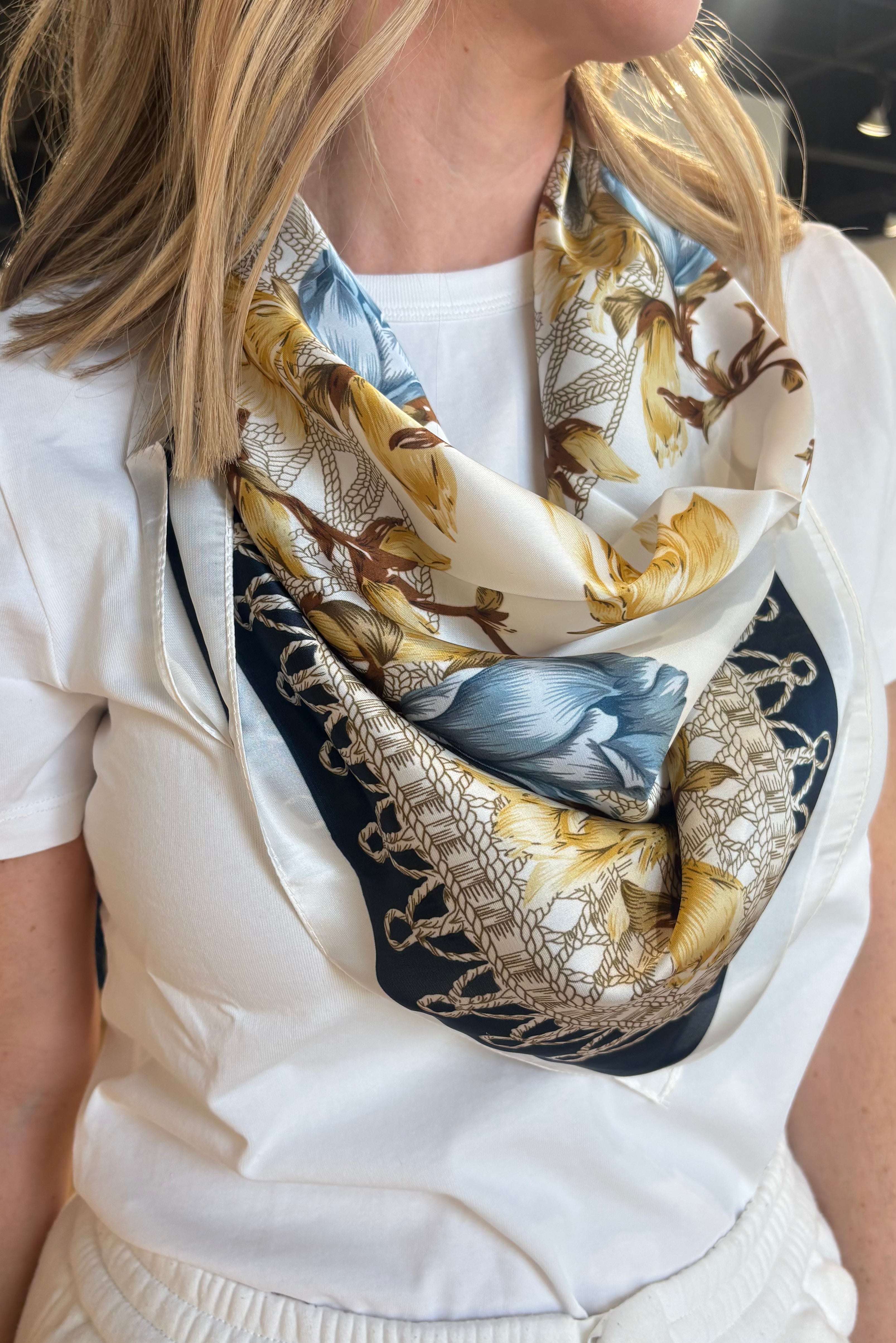 Person wearing a patterned scarf with a neutral background