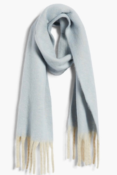 Cozy blue blanket scarf by Free People featuring long white fringe at the edges.