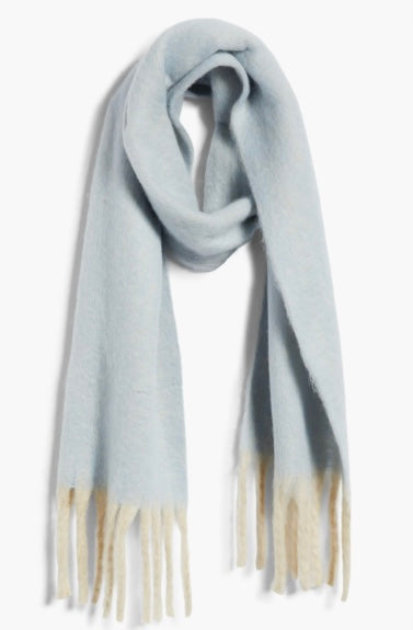 Cozy blue blanket scarf by Free People featuring long white fringe at the edges.