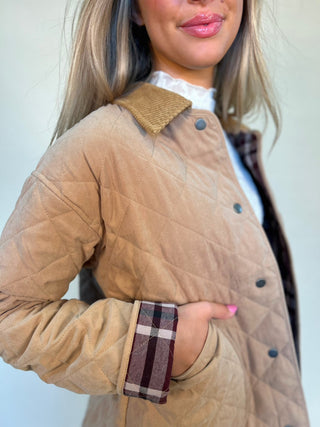 close-up detail shot of quilted barn jacket showing plaid detail on rolled up sleeve and corduroy collar and button details. shear boutique