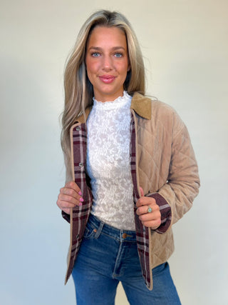 Front view of tan quilted barn jacket with red plaid lining and corduroy collar from shear boutique fall collection. Model is showing inside pattern detail 