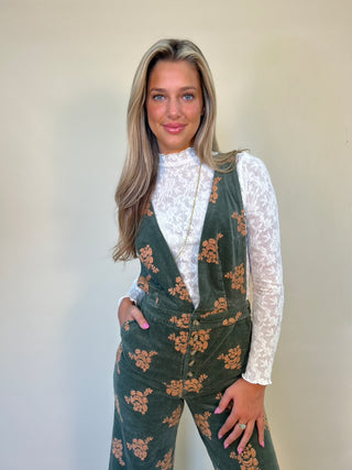 front of green mystree corduroy jumpsuit with white longsleeve textured knit top underneath. 