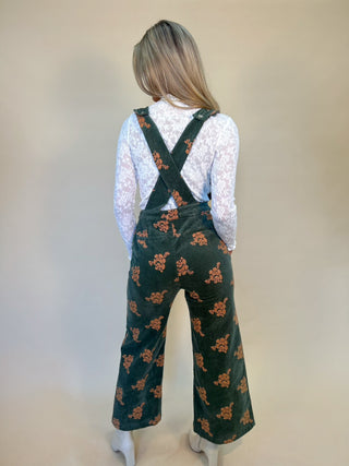 back of green corduroy jumpsuit, low back, adjustable button cross straps. high waisted, pockets.