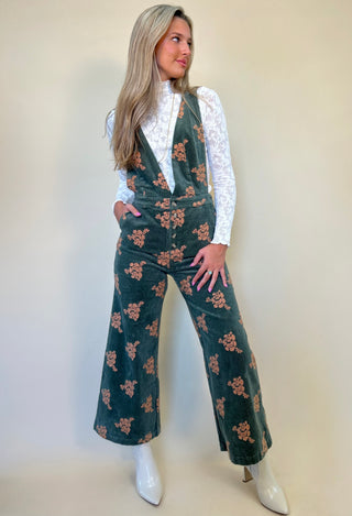 full length front view of green corduroy jumpsuit from shear boutique fall collection, paired with long sleeve white knit textured top and white boots.