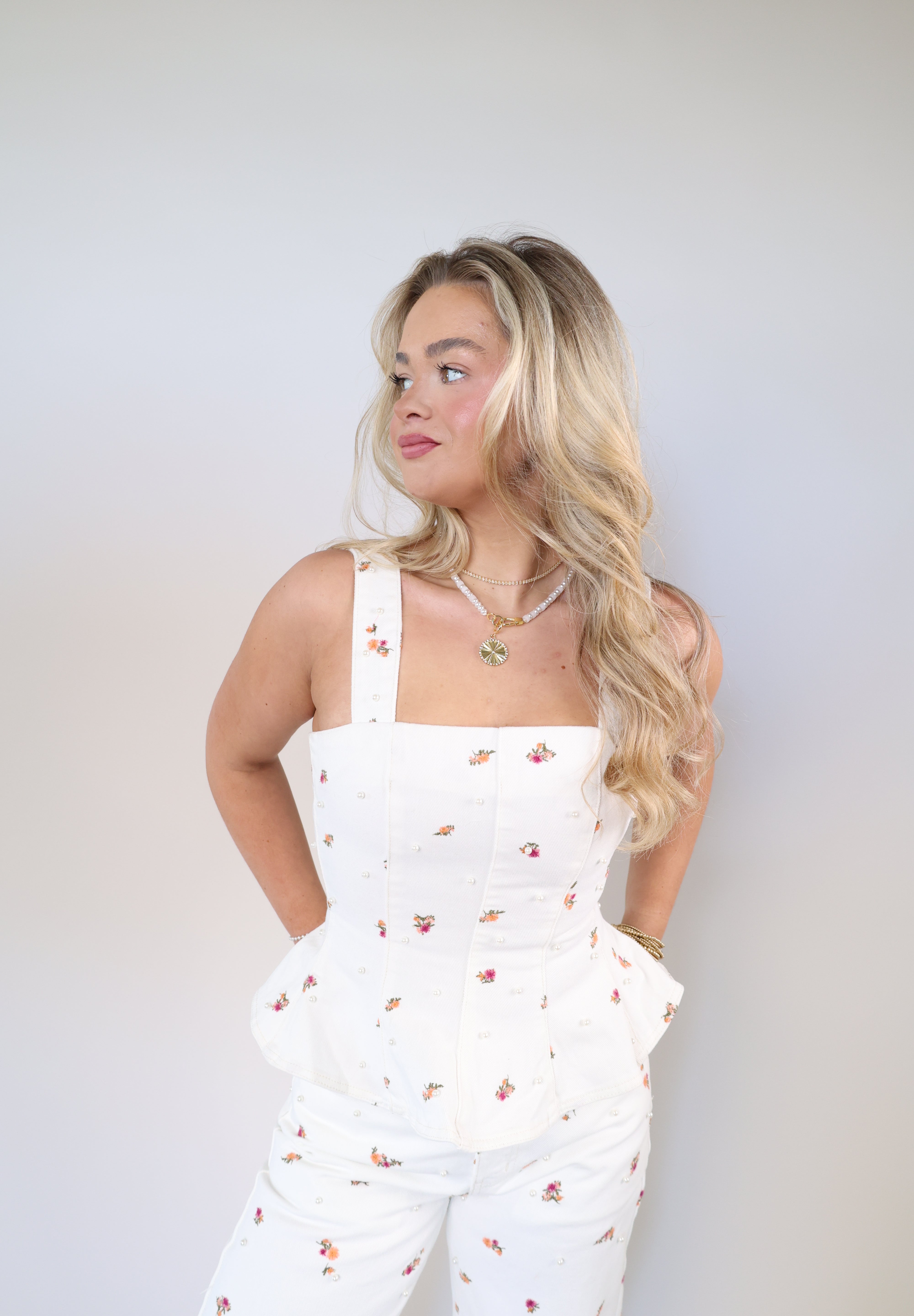 Structured denim top with colorful floral embroidery and sleeveless silhouette