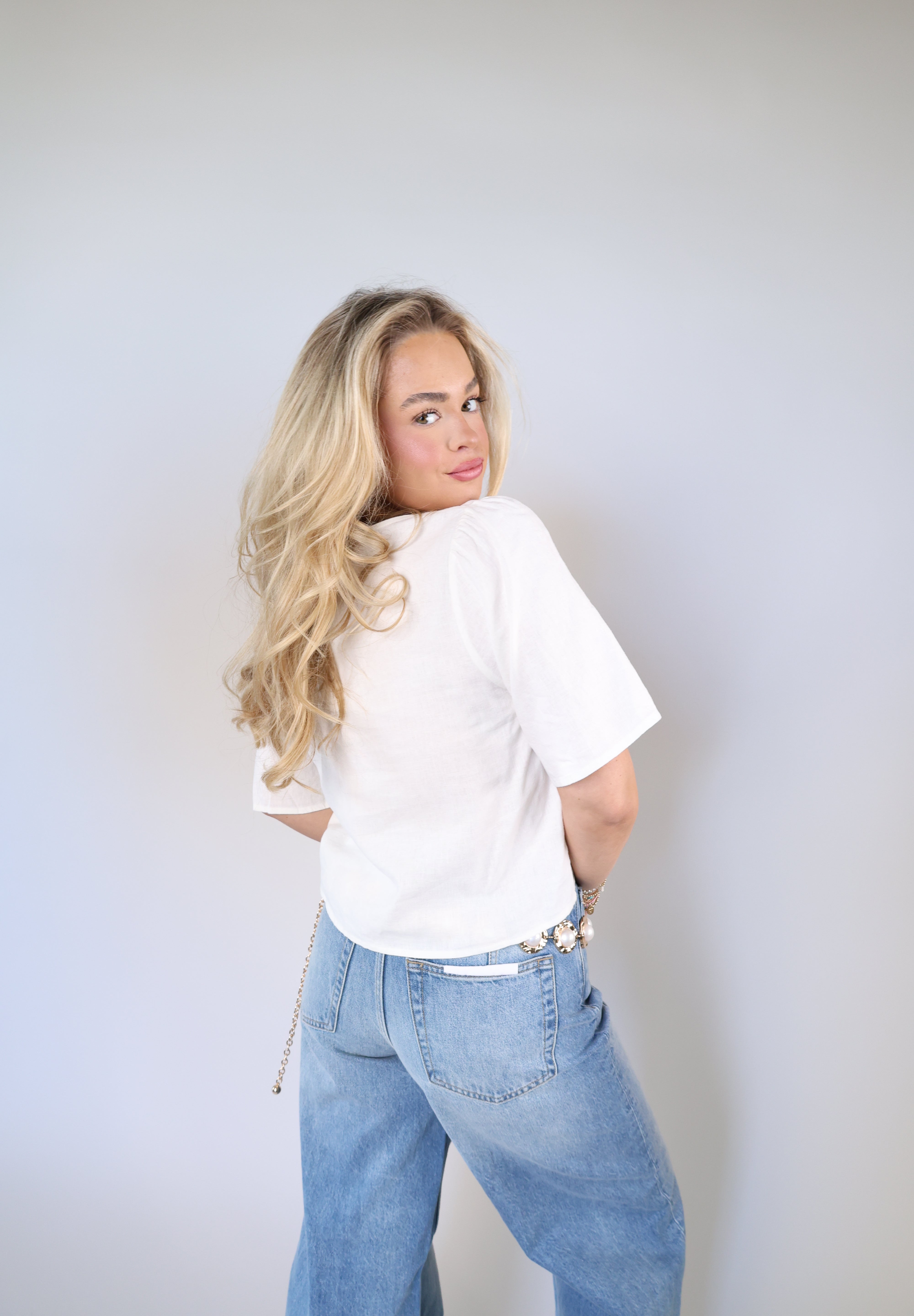 Feminine linen blouse with tie-front bows styled with wide leg denim and gold chain belt