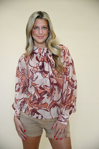 Model wearing Steve Madden Sorrel Horse Bow Tie Neck Top paired with Hampton Suede Cuffed Shorts from Shear Boutique, front view, terracotta pink long sleeve blouse with bow tie neck.