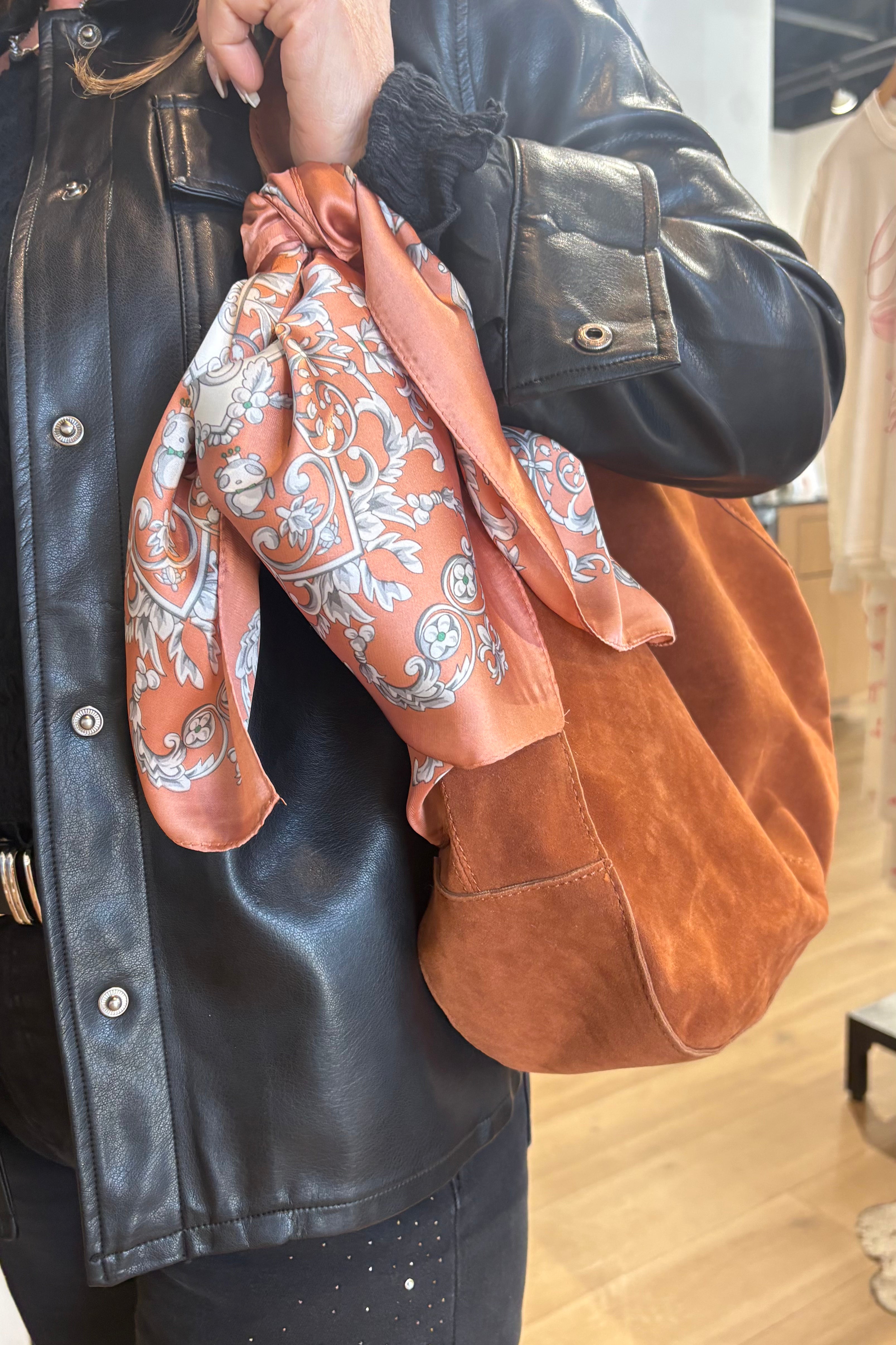 women holding a brown bag with a Rust colored scarf