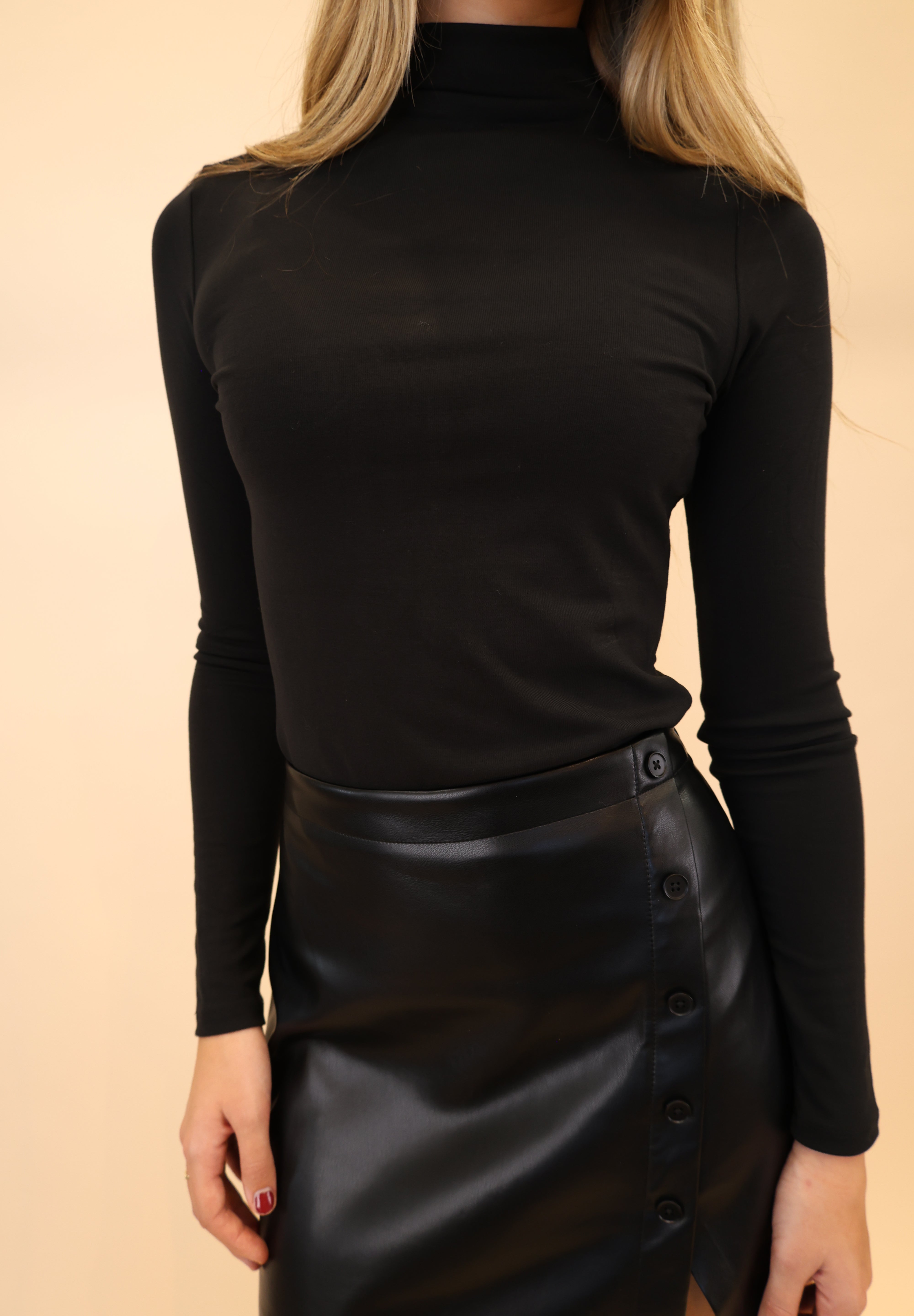 Model styled in a black fitted turtleneck Lira top. 