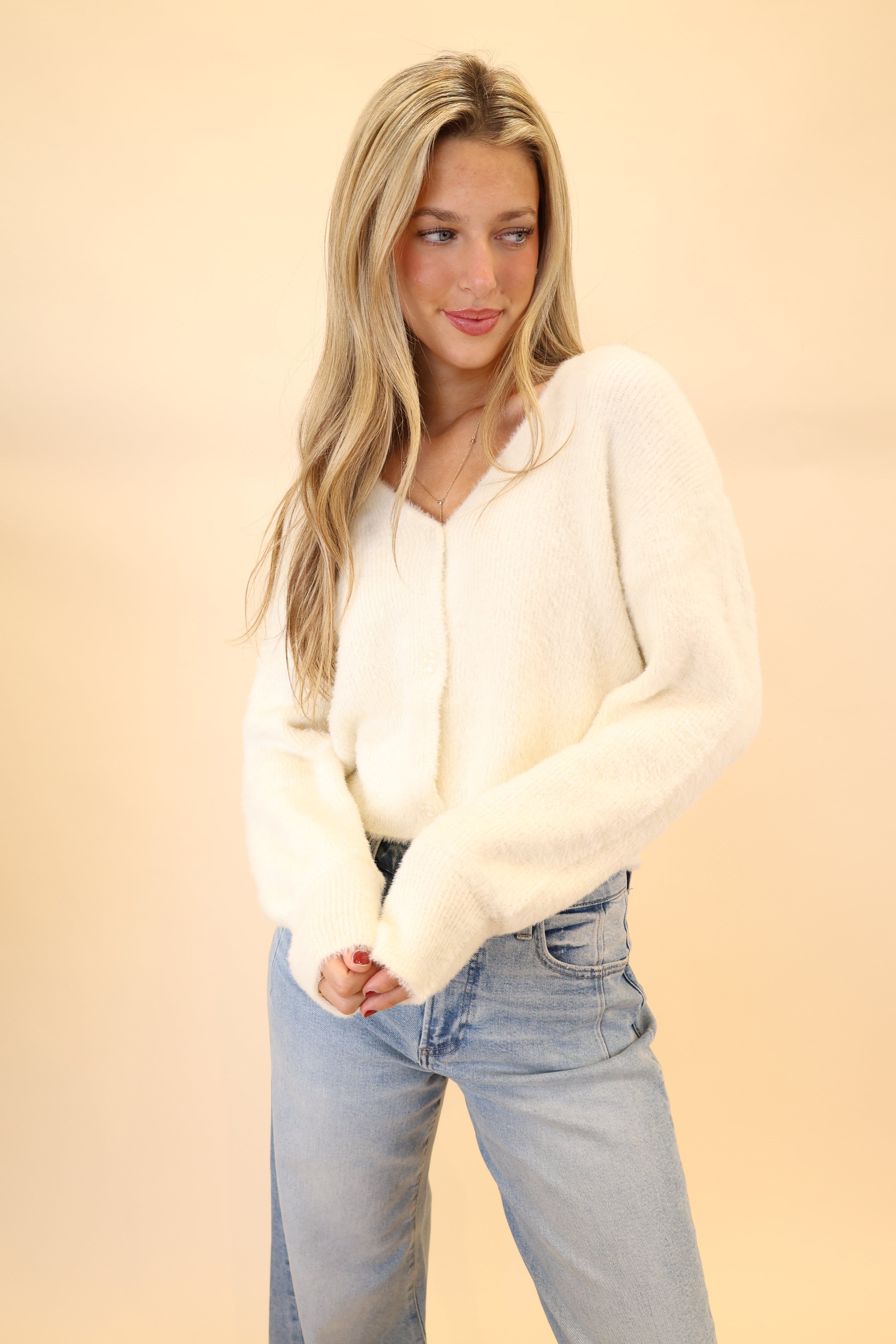 Woman styled in Z Supply Sadira white fluffy V-neck cardigan for a soft, casual look.