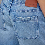 Close-up of blue jeans with a brand label on the pocket.