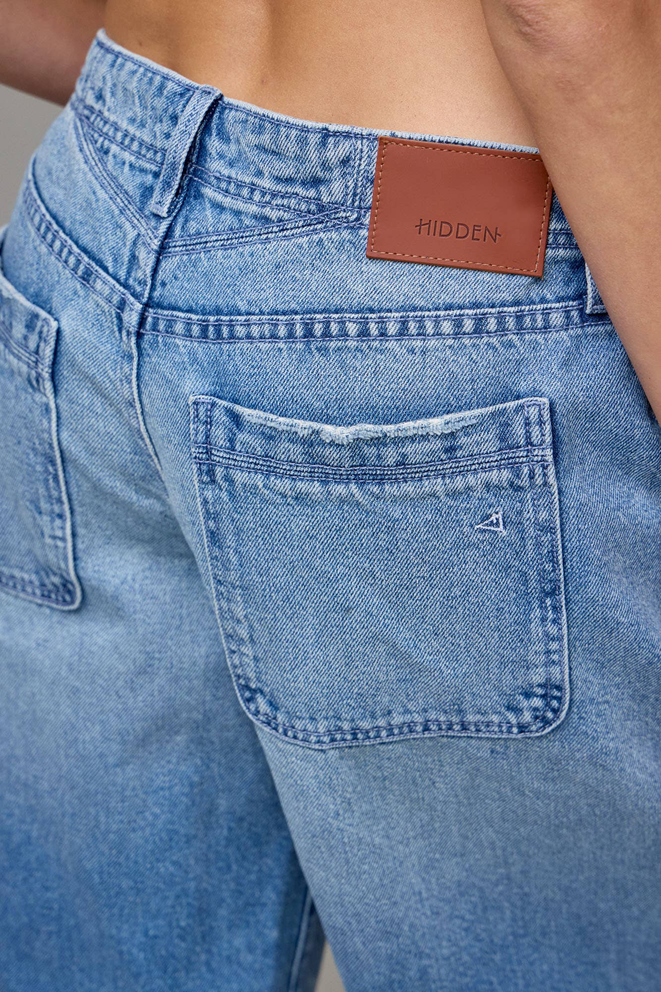 Close-up of blue jeans with a brand label on the pocket.