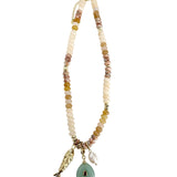 Gemelli Elikai beaded necklace with neutral beads and three dangling charms including a green stone pendant.