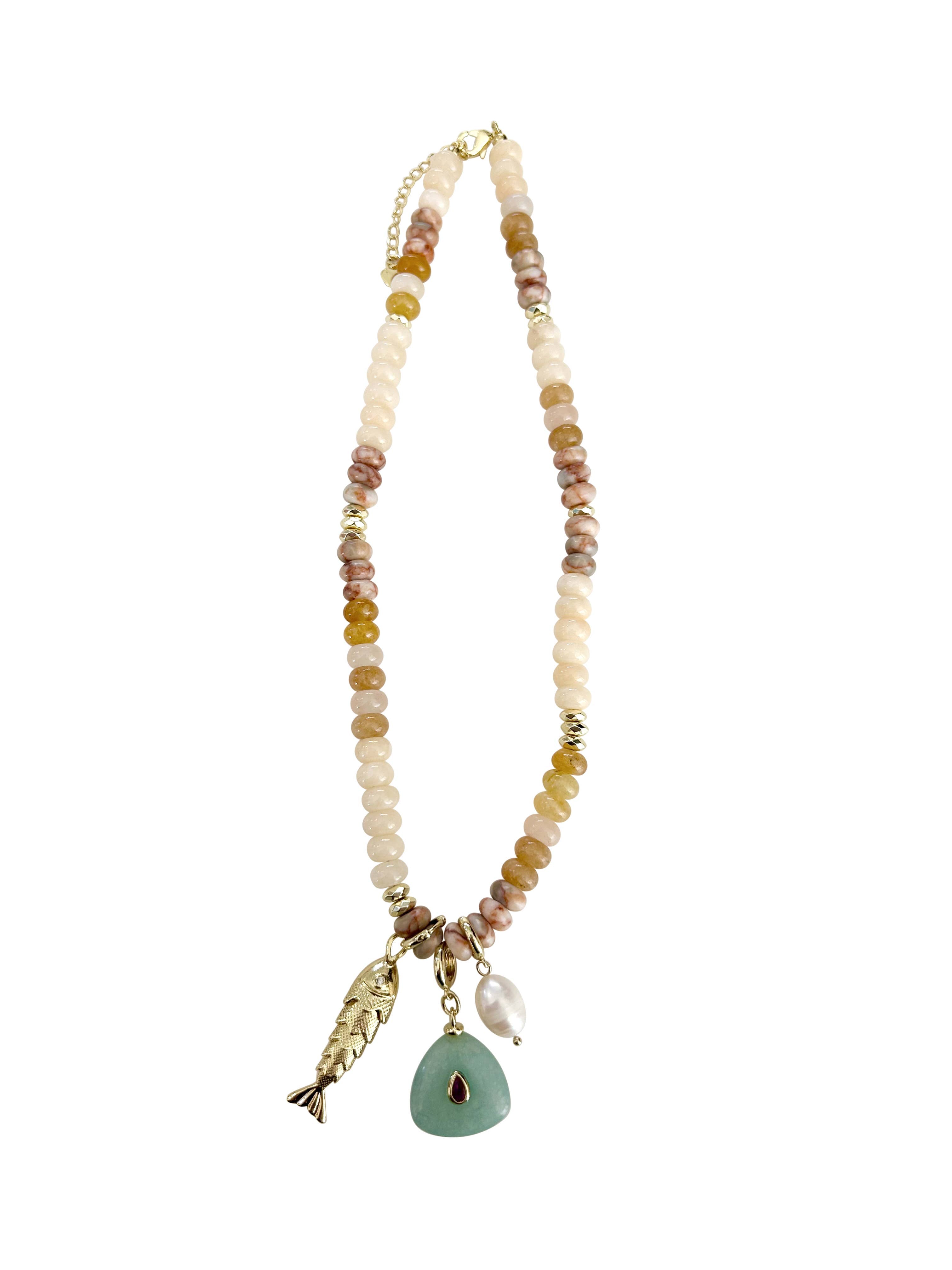 Gemelli Elikai beaded necklace with neutral beads and three dangling charms including a green stone pendant.