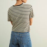 Person wearing a striped shirt and denim shorts against a plain background