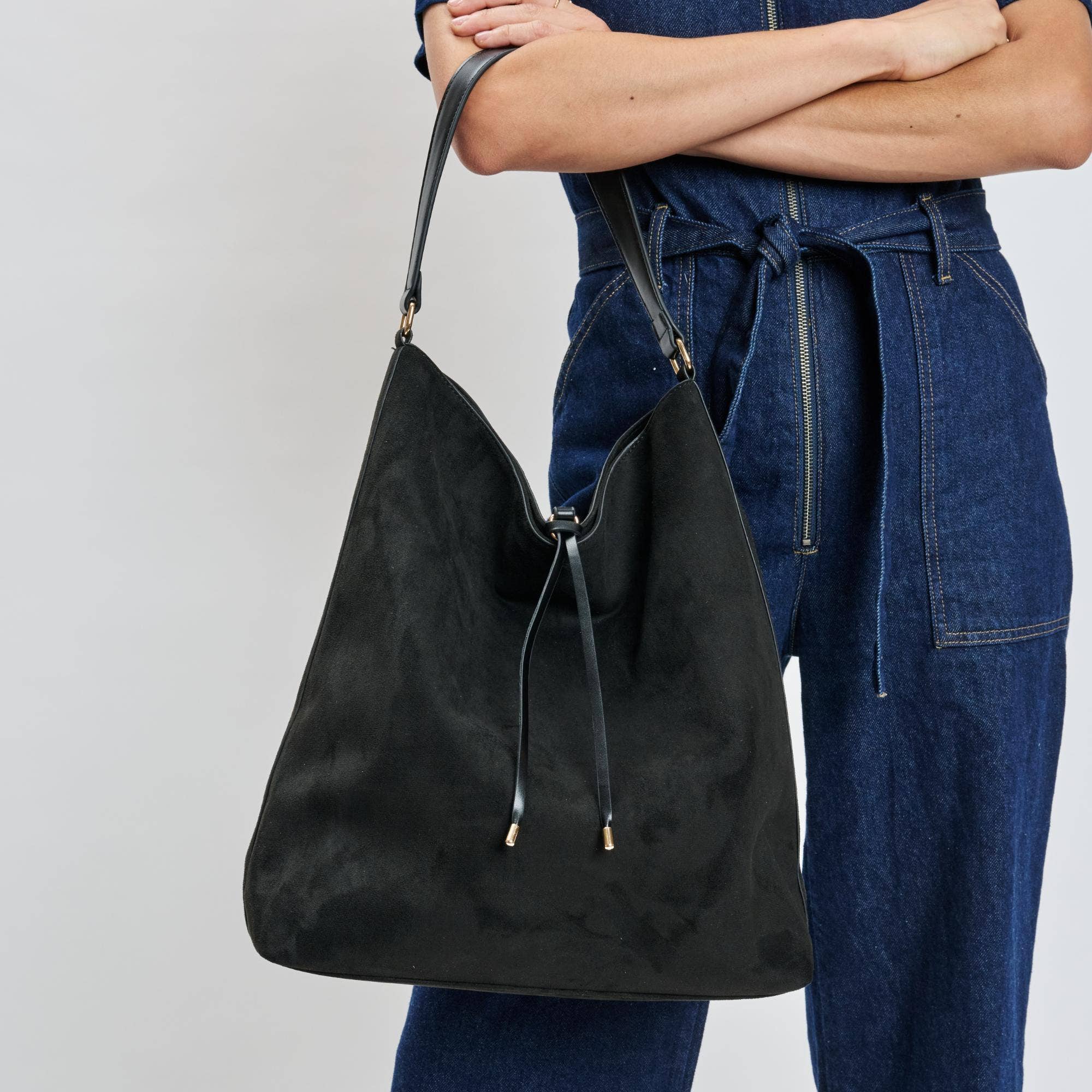 Close-up of Felicity Bucket black vegan leather handbag with gold hardware held by model wearing denim – chic everyday bucket bag – Shear Boutique
