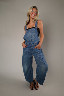 Woman wearing the Free People Good Luck Overall in Ultra Light Beam, featuring a relaxed oversized fit, wide-leg silhouette, and utility-inspired details.