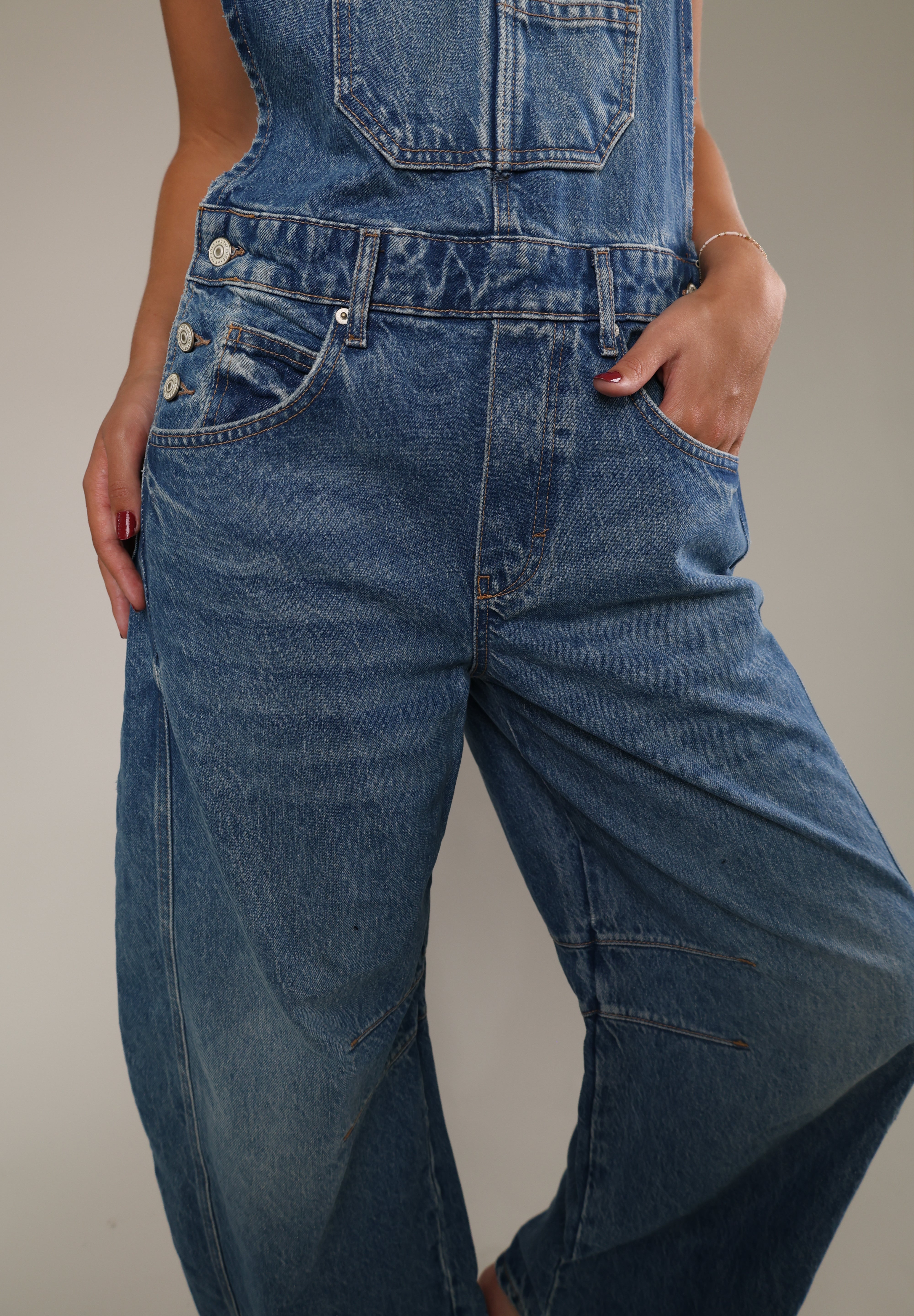 Casual women's denim overalls featuring adjustable shoulder straps, side button details, and a loose, comfortable fit.