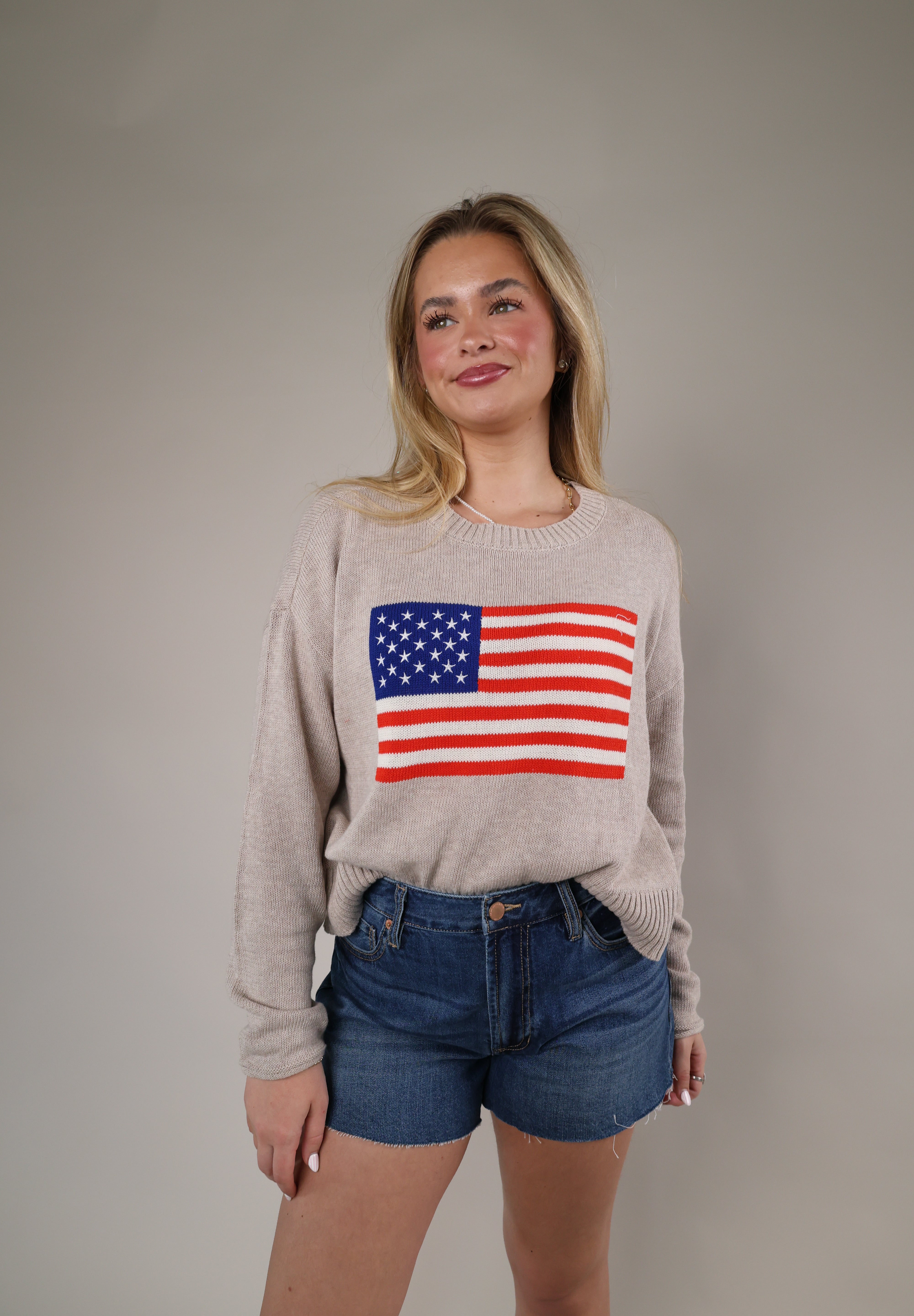 Neutral-toned Z Supply Sienna Patriot Sweater styled with denim shorts, featuring a vintage-inspired American flag graphic.