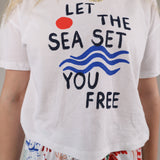 Woman wearing the Z Supply Vintage Sea Tee featuring a relaxed white fit with “Let the Sea Set You Free” graphic artwork.