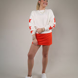 Relaxed fit cream sweatshirt featuring red star sleeve accents and an effortless everyday style perfect for casual layering.