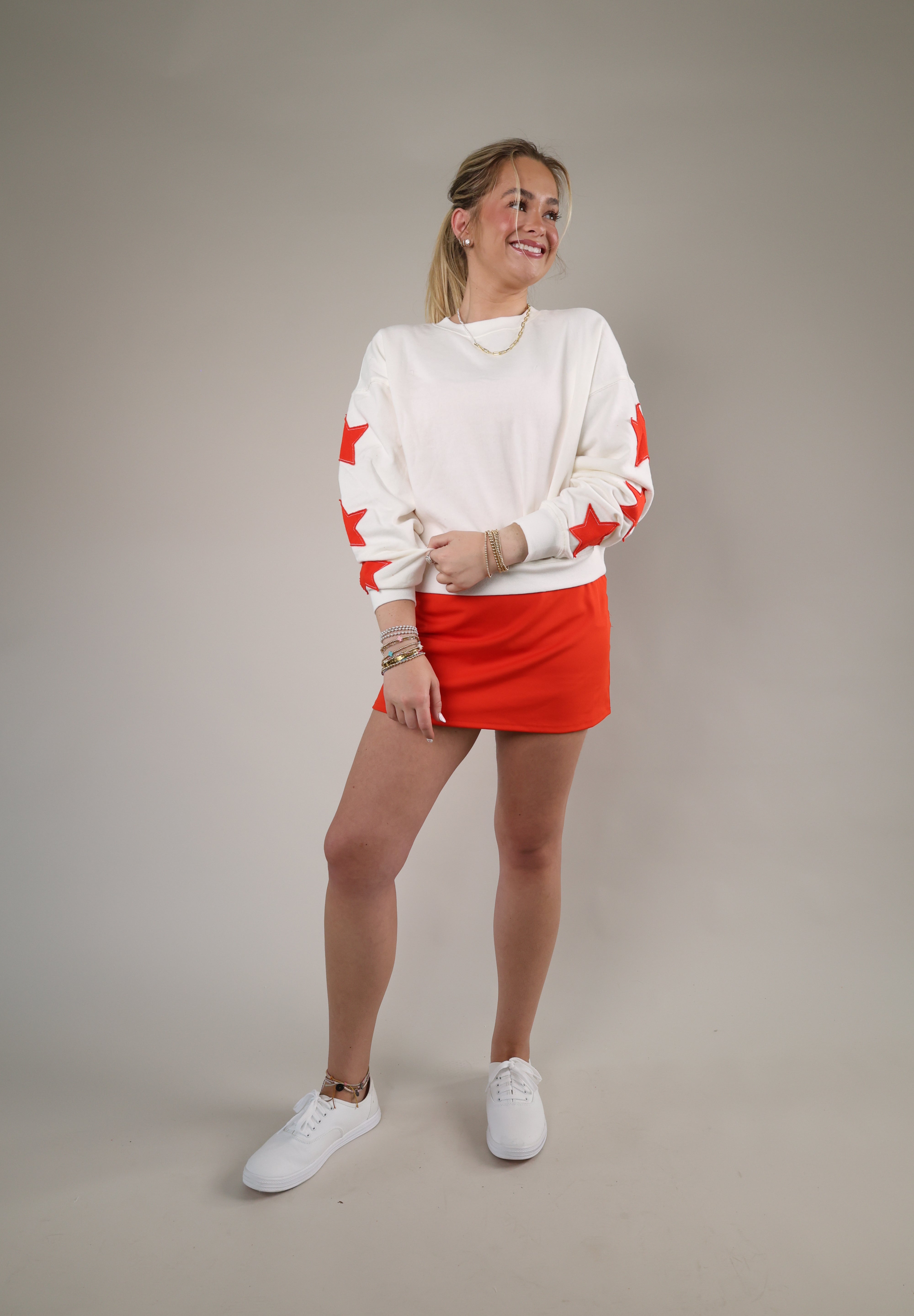 Relaxed fit cream sweatshirt featuring red star sleeve accents and an effortless everyday style perfect for casual layering.