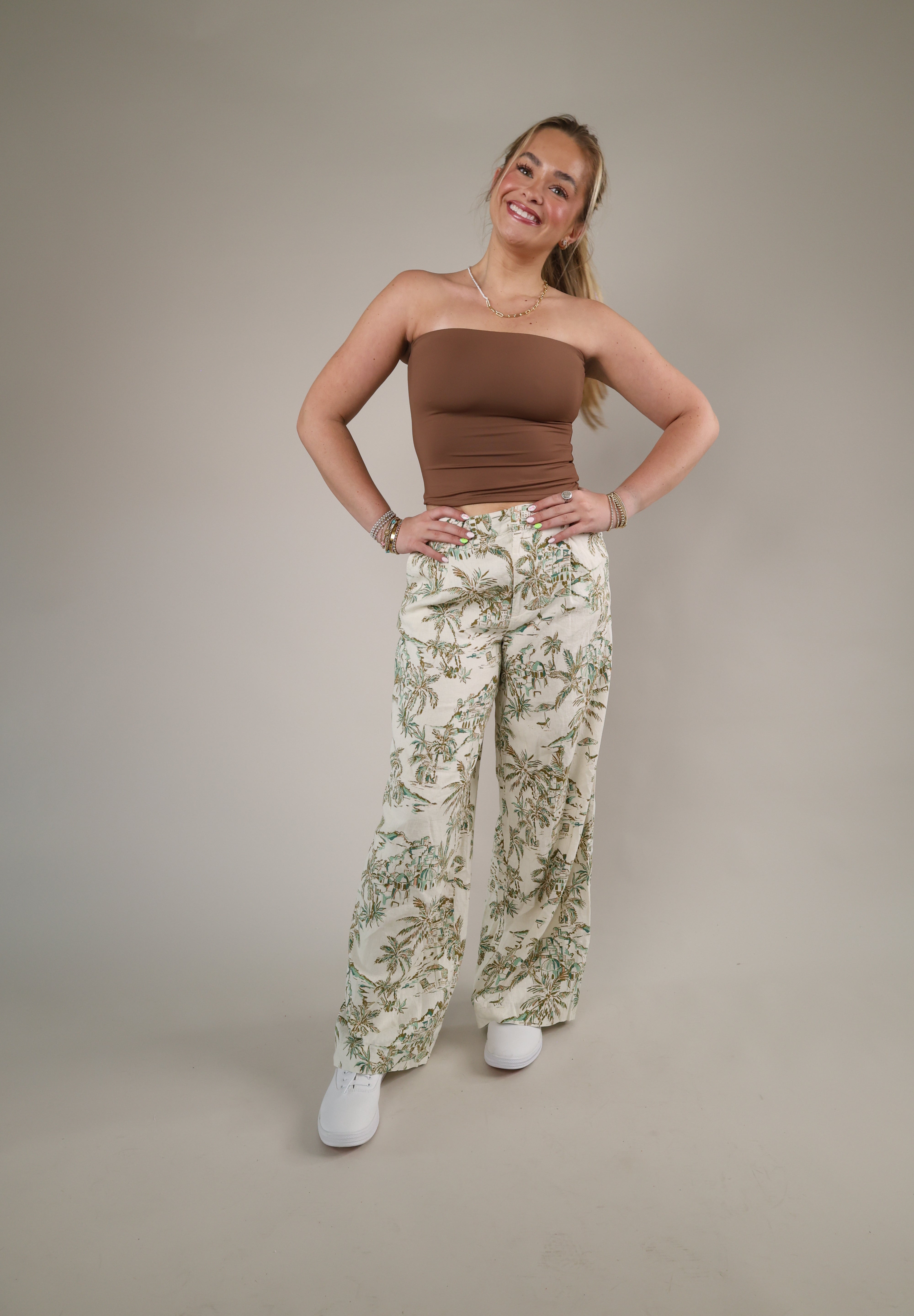 Wide-leg tropical print linen pants featuring a soft neutral background with green palm-inspired detailing and an airy relaxed fit.