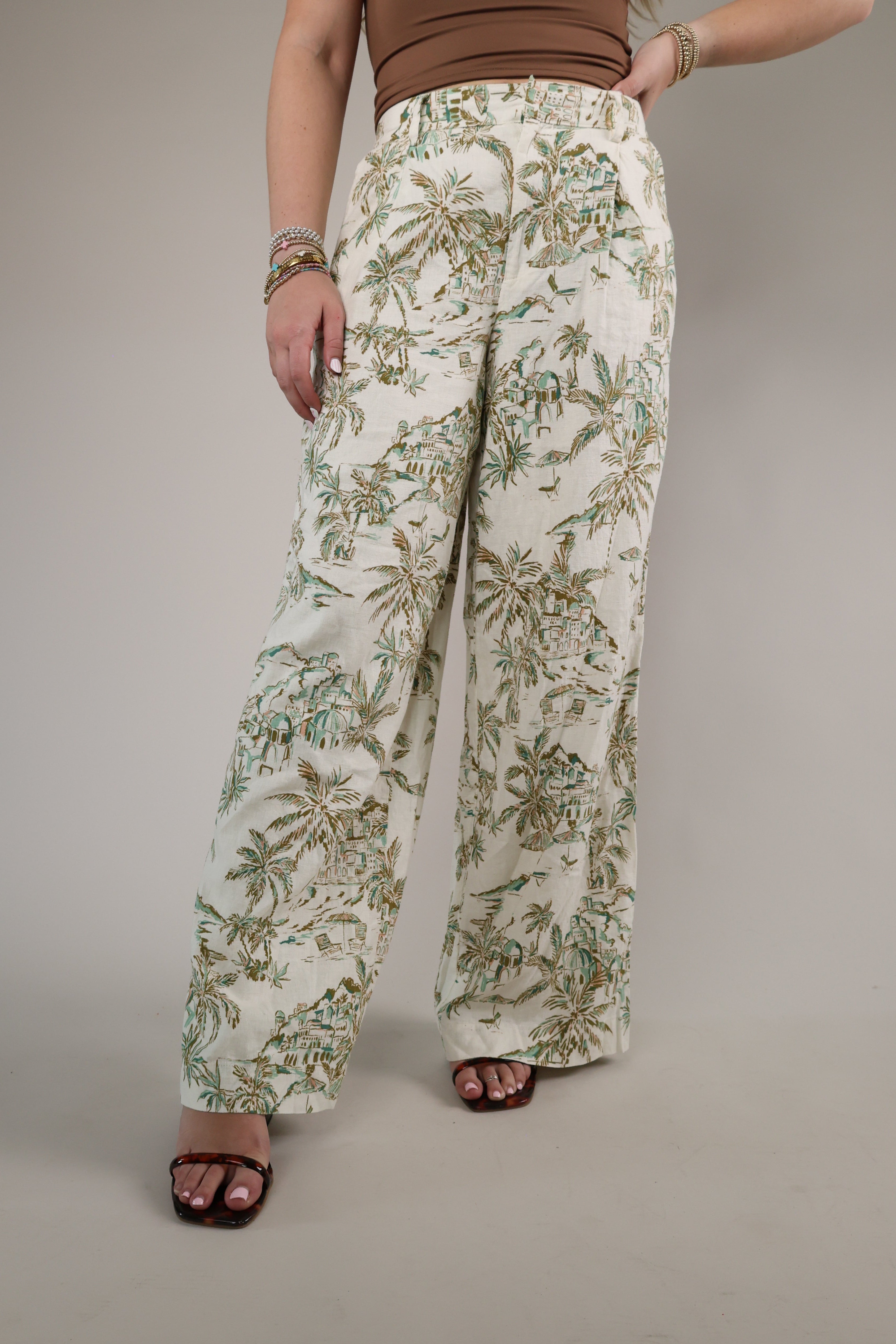 Woman wearing the Z Supply Overlook Tiki Tide Linen Pant featuring a relaxed wide-leg fit and tropical-inspired green leaf print.