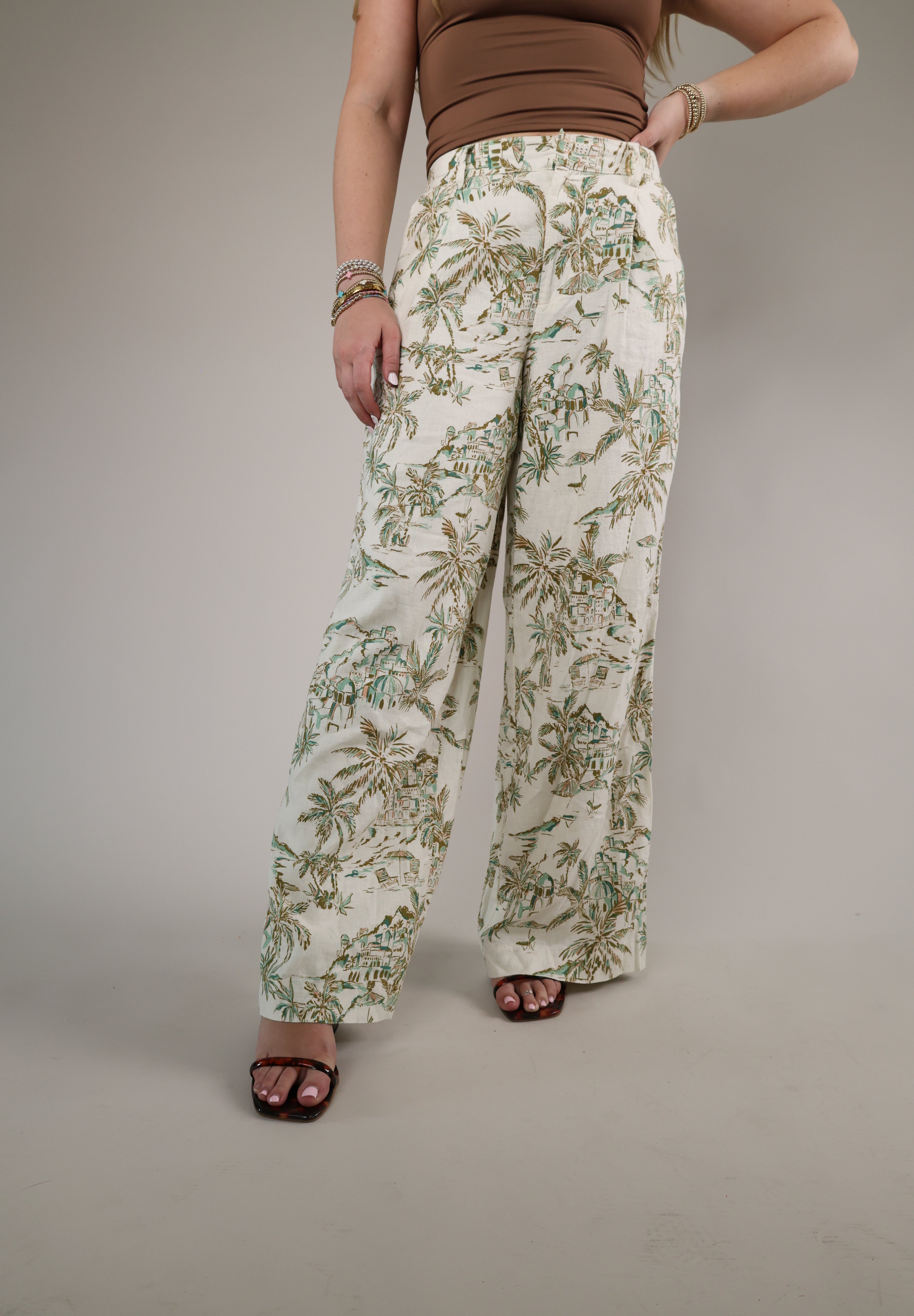 Woman wearing the Z Supply Overlook Tiki Tide Linen Pant featuring a relaxed wide-leg fit and tropical-inspired green leaf print.