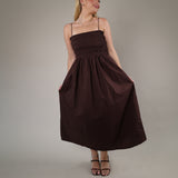 Flowy chocolate brown maxi dress featuring delicate straps, smocked detailing, and a breezy lightweight fabric perfect for summer occasions.